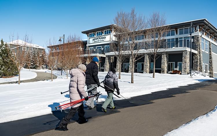 Family with skis passing beach club